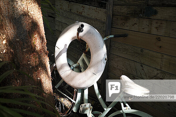 Vintage bicycle with a life ring leaning against an old wooden fence in dappled sunlight  Florida Keys  USA