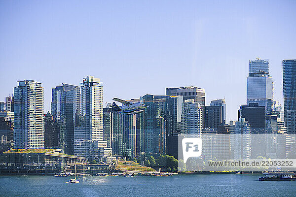 Seaplane flying above Burrard Inlet  downtown buildings in background