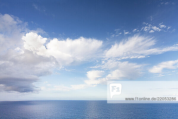 Puffy clouds above calm blue sea
