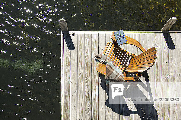 Overhead view of adirondack chair with book and blanket on pier on Lake Placid