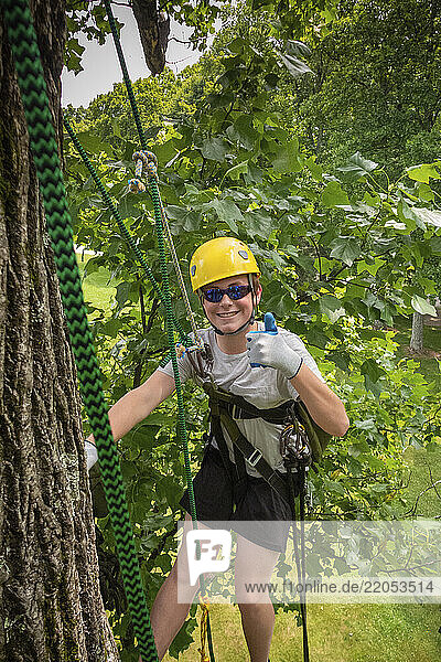 Portrait of smiling teenage boy (16-17) tree climbing