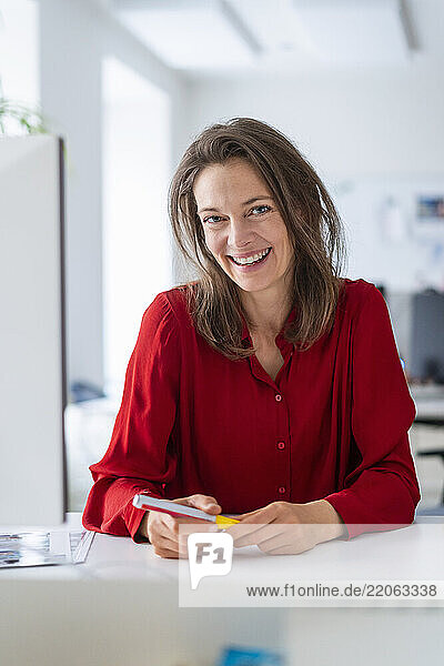 Happy woman sitting near desk at office