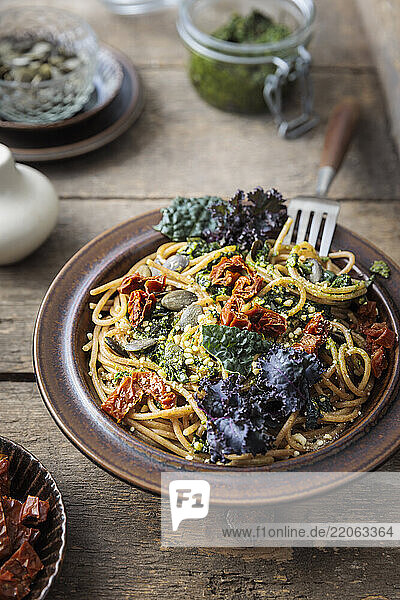 Spaghetti with kale  pesto  and dried tomatoes on a rustic wooden table