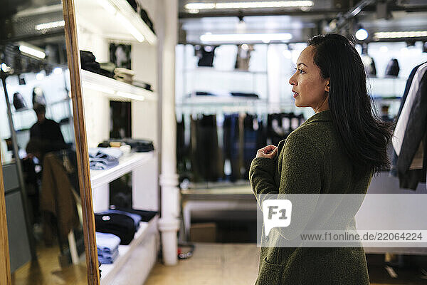 Woman looking in mirror at clothing store