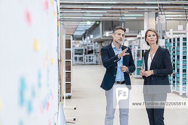 Businessman and businesswoman talking in a factory hall