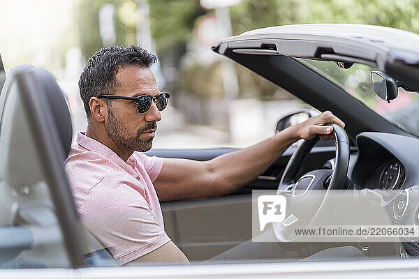Portrait of man wearing sunglasses driving convertible