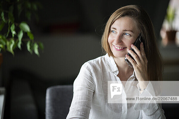 Smiling woman talking on smart phone at home