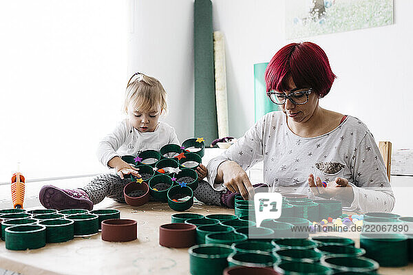Mother and daughter doing crafts at home with accessories to make a Christmas tree
