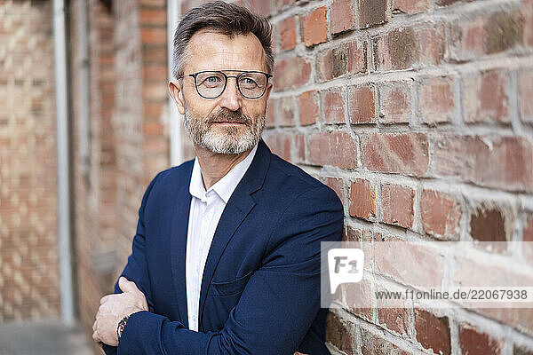 Portrait of businessman at brick wall looking sideways