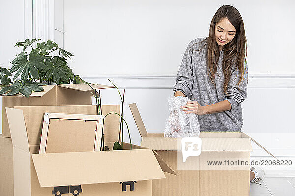 Woman carefully packing cardboard boxes with various items  ensuring they are secure and ready for shipping or storage