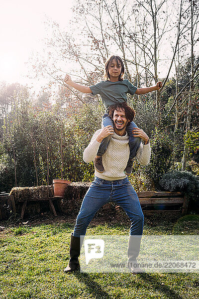 Father playing with his son  carrying him piggyback in a garden