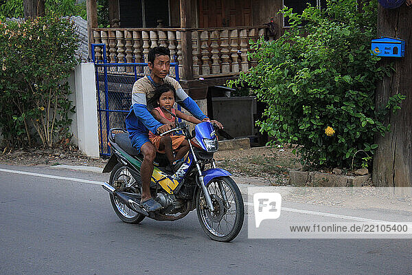 A father and his dauhter ride a motorcycle near Mae Sot  Thailand/ Un pere et sa fille roulent en scooter dans une rue pres de Mae Sot Thailande