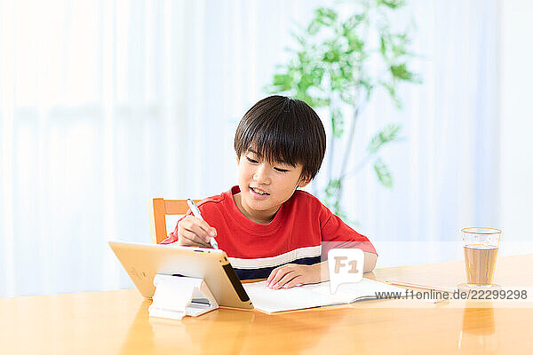 A Young Boy Sitting At A Table With A Tablet