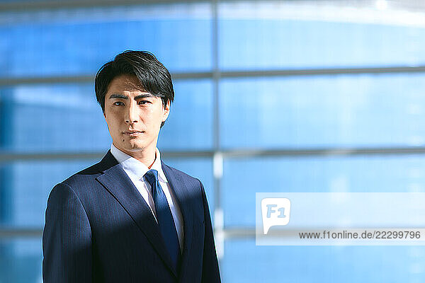 Japanese Businessman In Suit And Tie Standing In Front Of Window