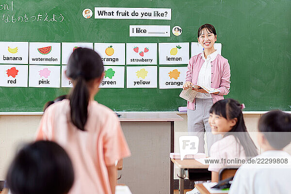 Japanese Teacher With Her Students In Front Of A Blackboard