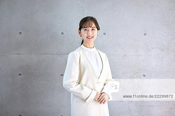 Japanese Woman In A White Suit Standing In Front Of A Wall