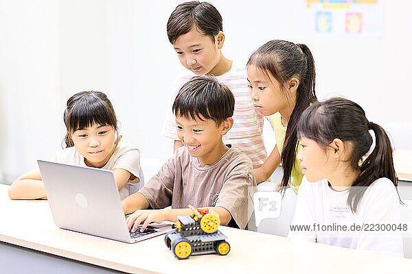 Group Of Japanese Children Looking At A Laptop