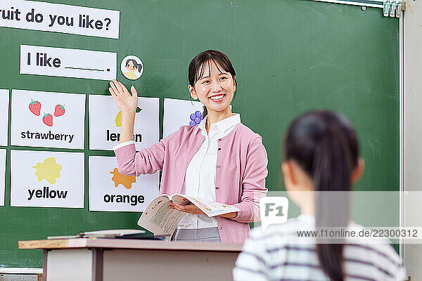 Japanese Teacher With Her Students In Front Of A Blackboard