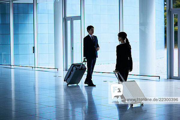 Two People In Business Attire Walking Through An Airport