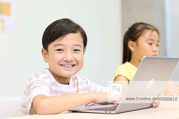 A Young Boy Smiles While Using A Laptop