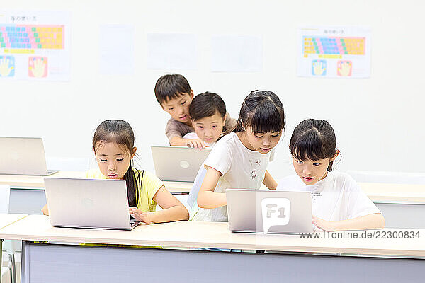 Group Of Japanese Children Using Laptops In A Classroom