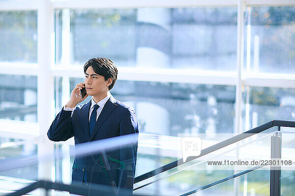 Japanese Businessman Talking On Phone In Office Building