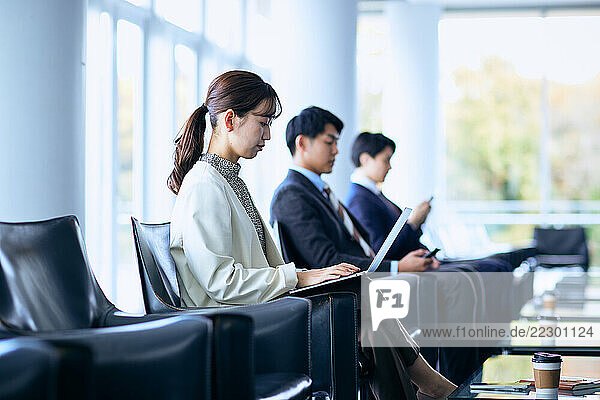 Business People Sitting In Chairs With Laptops