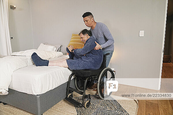 Man helping disabled friend getting out of bed