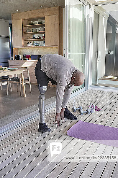 Man with leg prosthesis exercising on patio