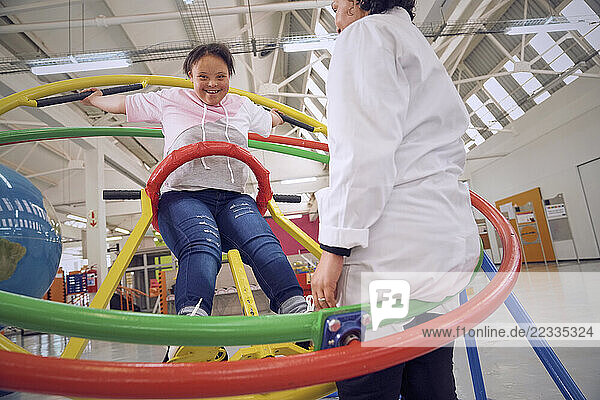 Teenager with down syndrome plying on gyroscope at science center