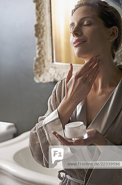 Woman applying cream on her neck