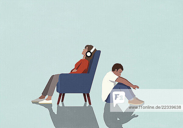 Man sitting on floor behind woman listening to music with headphones and relaxing in armchair