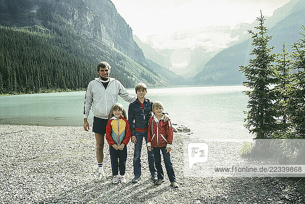 Portrait father and children on vacation  standing at sunny mountain lake