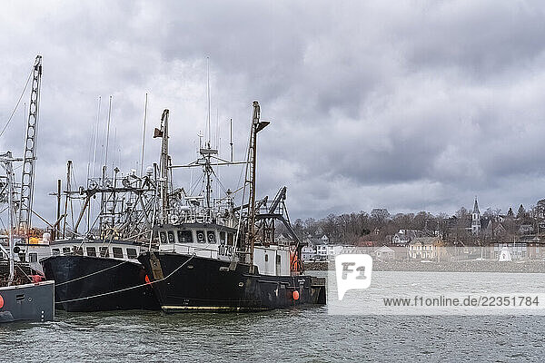Boats in the Digby harbour with the town site in the background. Clouds hang low over the town and harbour; Digby  Nova Scotia  Canada