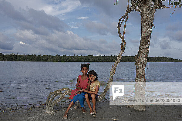Children playing in front of their house close to the river at the Kalabogi village in Khulna  Bangladesh  on 04 September 2023. In the coastal areas of Southern Bangladesh like Kalabogi  people‘s livelihoods depend entirely on nature. Climate change has severe impacts on the natural environment. The consequences range from rising sea levels leading to salinization of soils and groundwater to erratic rainfall patterns and more frequent and destructive tropical cyclones. People living in coastal areas fight for their survival every day; Khulna  Dhaka  Bangladesh