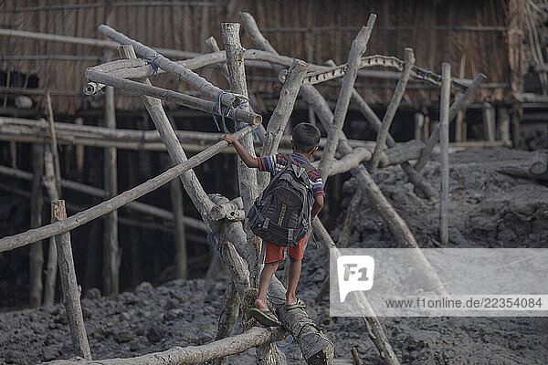 Boy crosses a bamboo bridge on his way to school in the Kalabogi village  close to the Sundarbans mangrove forest in Bangladesh  on 26 April 2021. Every year the water level of the river rises higher. The villagers build bamboo bridges to be able to move during high tide and flood times; Khulna  Dhaka  Bangaldesh