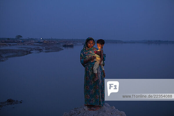 Woman with her son poses for a picture in the coastal hanging village Kalabogi where people are heavily affected by climate change  in the Sundarbans mangrove forest  Bay of Bengal  Bangladesh  on 11 February 2020. She had to move her house four times in the past years because of flooding and erosion; Khulna  Dhaka  Bangladesh