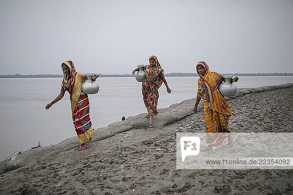 Women need to walk from their house around 1/2 kilometer to collect drinking water at the Kalabogi village in Khulna  Bangladesh  on 01 September 2023. In the coastal areas of Southern Bangladesh like Kalabogi  people‘s livelihoods depend entirely on nature. Climate change has severe impacts on the natural environment. The consequences range from rising sea levels leading to salinization of soils and groundwater to erratic rainfall patterns and more frequent and destructive tropical cyclones. People living in coastal areas fight for their survival every day; Khula  Dhaka  Bangladesh