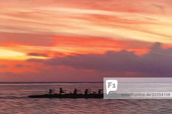 Motion blurred image of outrigger canoe paddlers at sunset on Tumon Bay off Guam  Micronesia; Asan  Guam  Micronesia