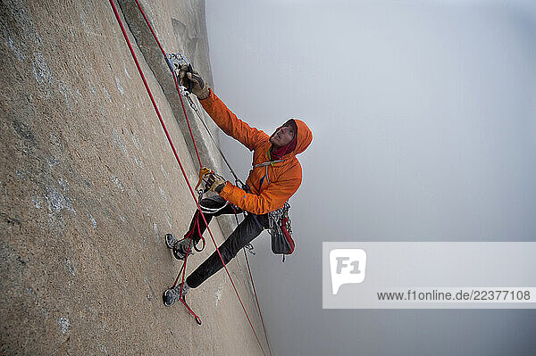 Tommy Caldwell jummaring on The Dawn Wall as a storm rolls into the valley in Yosemite National Park  California.
