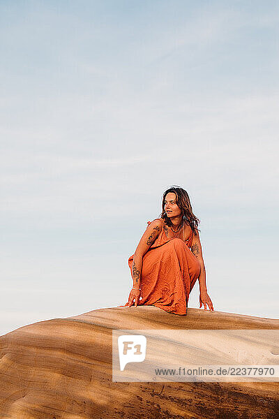Woman crouching on top of a sandstone rock formation