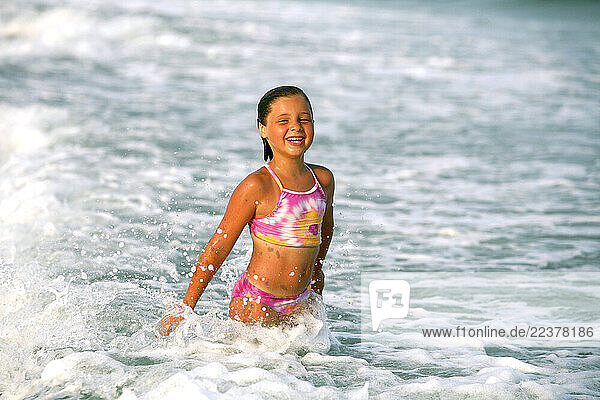 A young girl plays in the surf.