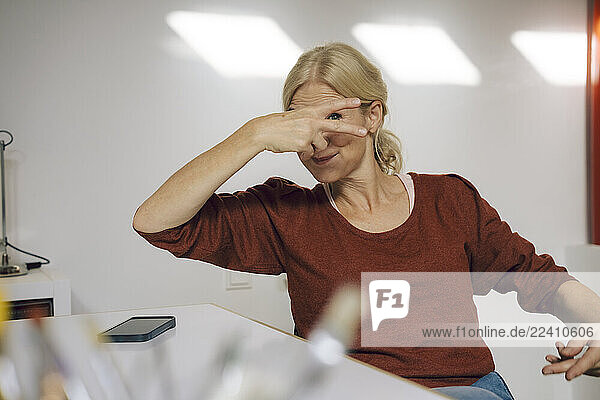 Woman in an office covering her face with her hand