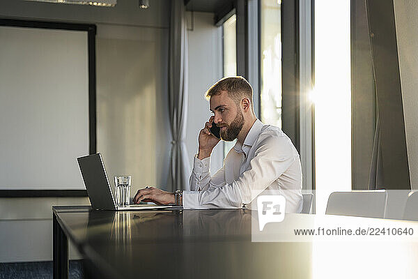 Young man making a phone call in a modern office at sunset