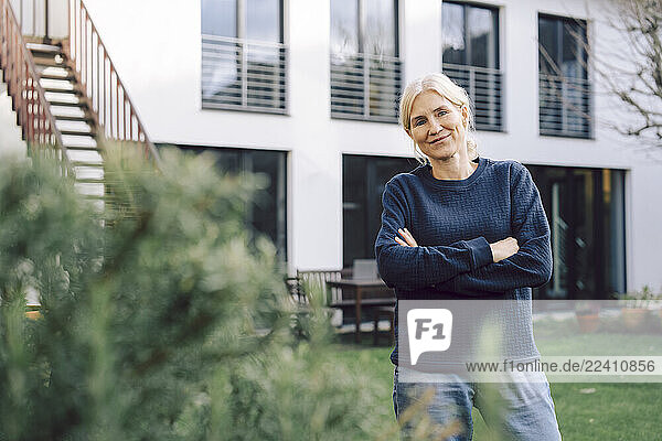 Woman gardener smiling with crossed arms in a garden