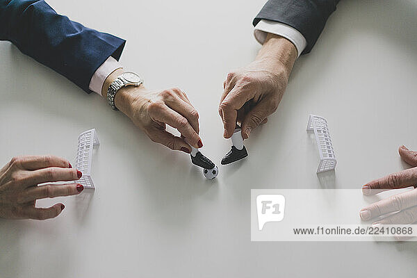 Close-up of businesswoman and businessman playing table football in office