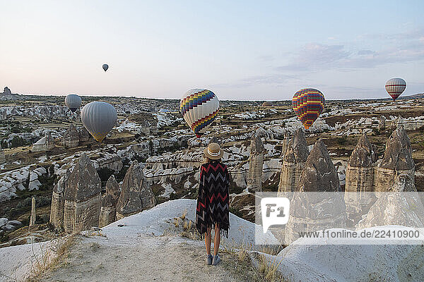 Young woman and hot air balloons in the evening  Goreme  Cappadocia  Turkey