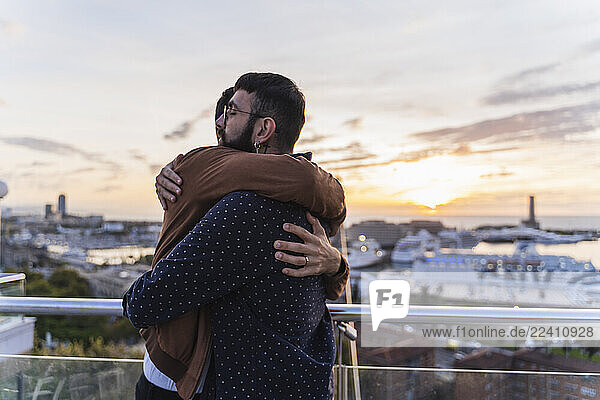 Gay couple hugging on lookout above the city with view to the port  Barcelona  Spain