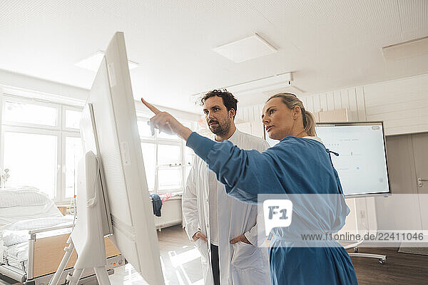 Doctors consulting and discussing in a clinic using a screen