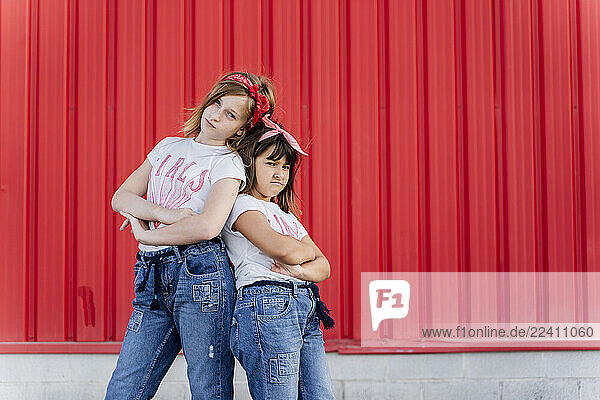 Sisters standing in front of a red wall